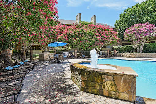 A pool area with a waterfall and a stone wall.
