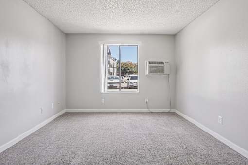 A room with a window and a wall-mounted air conditioner unit. at Windmill Apartments, Colorado Springs, CO, 80916