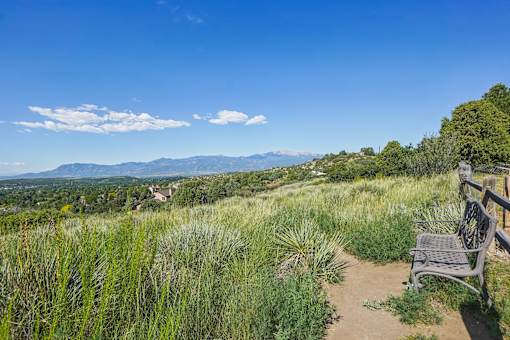 A bench overlooks a grassy field with a mountain range in the distance.