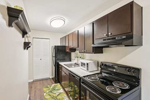 A modern kitchen with a black stove top oven and a white microwave. at Sarasota South Apartments, Bradenton, Florida