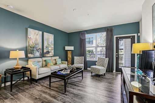 Living room with teal accent wall and balcony access at The Arbor Walk Apartments, Tampa, 33617