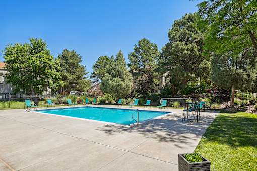 A pool surrounded by trees and chairs.