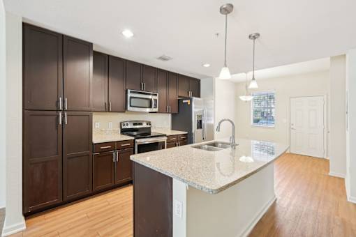 A kitchen with brown cabinets and a white island. at The Dakota, Florida, 33458