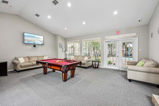 A room with a pool table and a television.