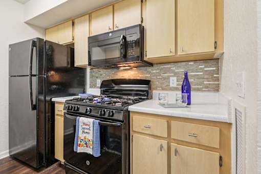 A kitchen with a black refrigerator and stove top oven. at University Park Apartments, Florida