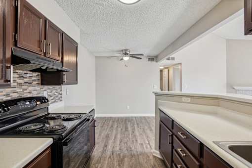 A kitchen with dark wood cabinets and a black stove top oven. at Deer Crest Apartments, Broomfield