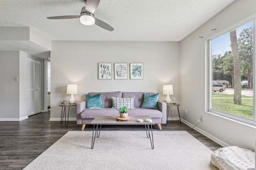 A living room with a grey couch and a grey rug. at Lakeside Glen Apartments, Melbourne, Florida