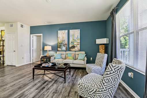 Spacious living room with patterned accent chairs at The Arbor Walk Apartments, Tampa, Florida