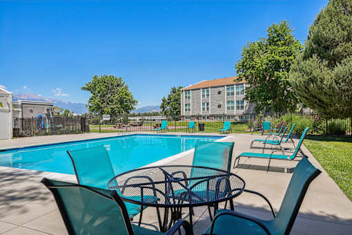 A pool area with chairs and a table.