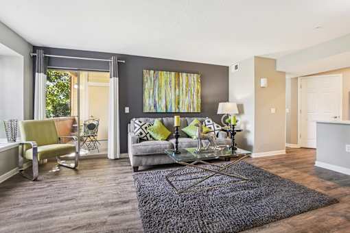 A living room with a grey couch and a glass coffee table.