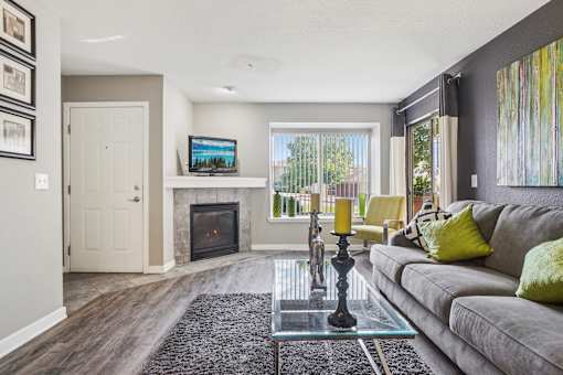 A living room with a grey couch and a fireplace.