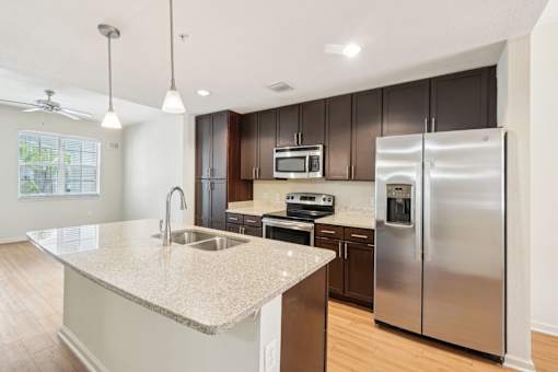A kitchen with a granite countertop and stainless steel appliances. at The Dakota, Jupiter, FL, 33458