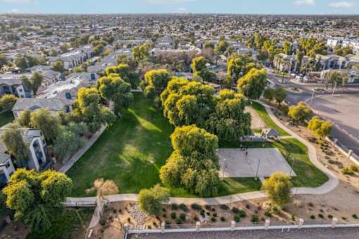 A park with a basketball court surrounded by trees and houses at Sweetwater At Metro North Apartments, Phoenix  85029