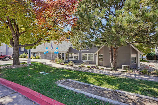 A tree with red leaves is in front of a house. at Windmill Apartments, Colorado Springs, CO, 80916