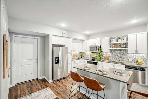 a kitchen with stainless steel appliances and a island with three chairs at Edge75, Naples, Florida 34104