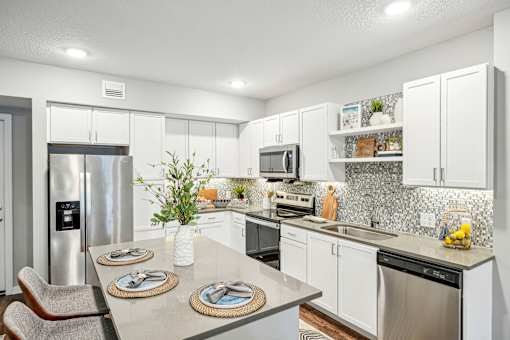 a kitchen with stainless steel appliances and white cabinets at Edge75, Naples, Florida 34104