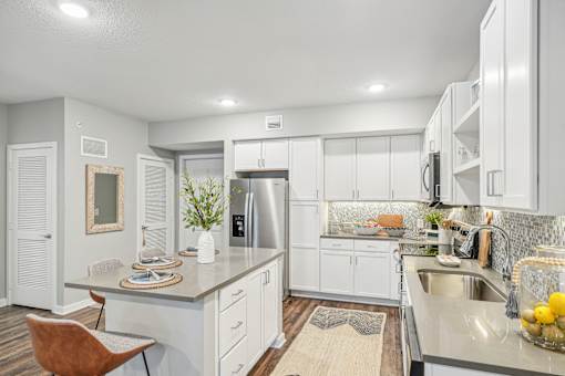 a white kitchen with stainless steel appliances and white cabinets at Edge75, Naples, Florida 34104