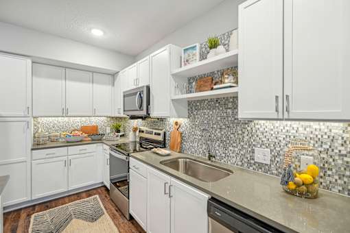 a kitchen with white cabinets and a stainless steel sink at Edge75, Naples, Florida 34104