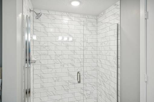 a large shower with white tile walls and a glass shower door at Edge75, Naples, Florida 34104