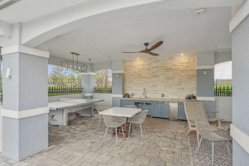 a patio with a dining area and a kitchen with a table and chairs at Edge75, Naples, Florida 34104
