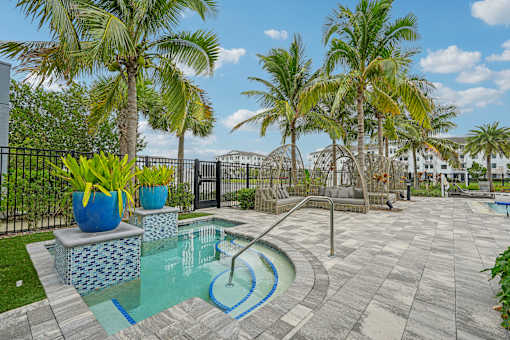 a swimming pool with palm trees and a black fence at Edge75, Naples, Florida 34104