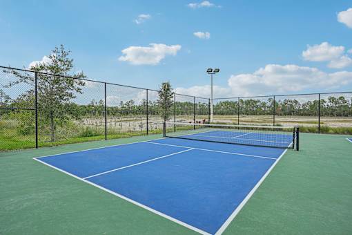 a blue and green tennis court with a fence around it at Edge75, Naples, Florida 34104