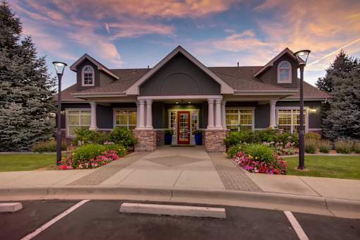 the front of a house with a driveway and a sunset at Heritage at Stone Mountain, Northglenn, CO, 80233