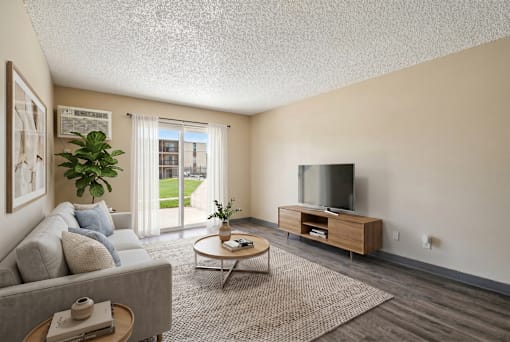A living room with a grey couch, a wooden coffee table, a flat screen TV and a plant at Broadmoor Springs, Colorado Springs, CO, 80906