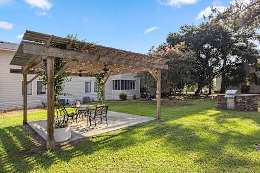 A wooden pergola with a table and chairs under it. at River Crossing Apartments, Thunderbolt, GA