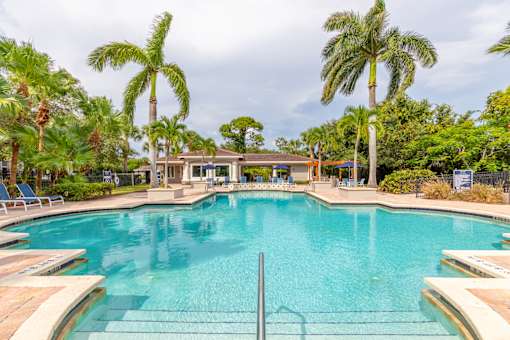 a large swimming pool with palm trees in the background at Heritage Bay, Jensen Beach, FL