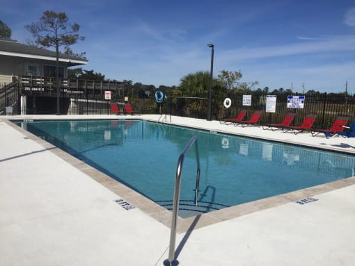 Swimming pool with red chairs around iit at River Crossing Apartments, Thunderbolt, GA, 31404