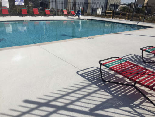 Wwimming pool with a red chairs next to it at River Crossing Apartments, Thunderbolt, GA, 31404