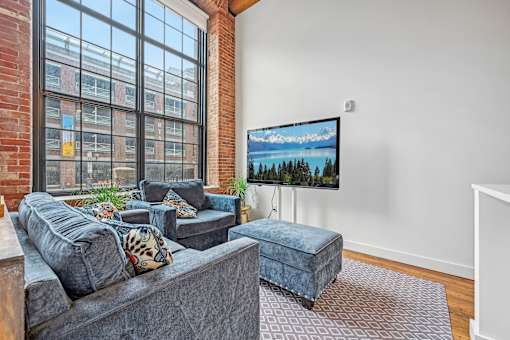 a living room with a large window and a couch and a chair at Riverwalk Apartments, Lawrence, MA