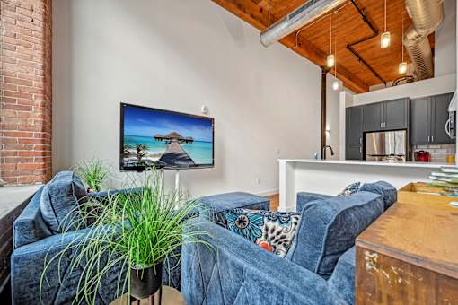 a living room with couches and a kitchen with a tv on the wall at Riverwalk Apartments, Lawrence, MA