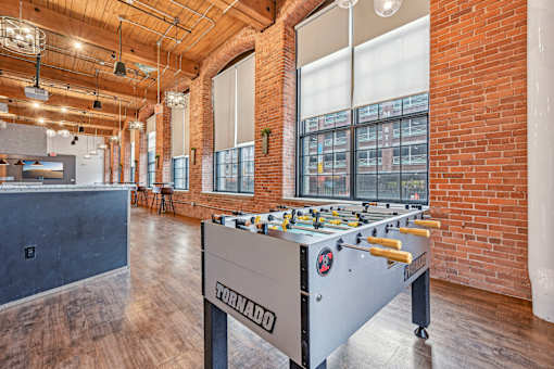 a foosball table in a room with brick walls and a bar at Riverwalk Apartments, Lawrence, MA