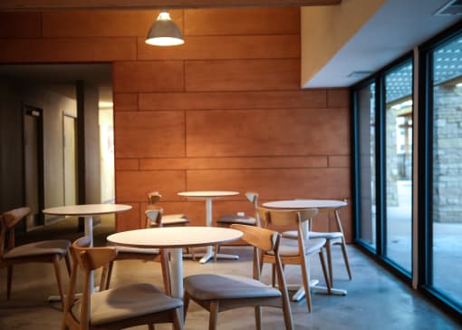 a dining room with tables and chairs in front of a wood wall at Spyglass Creek, Denver, 80224
