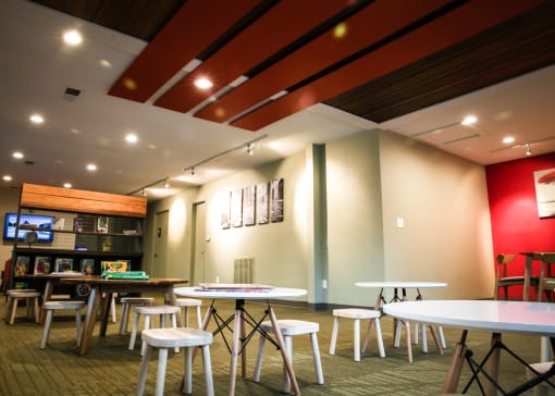 a dining area with tables and stools and a bar in the background at Spyglass Creek, Denver, 80224