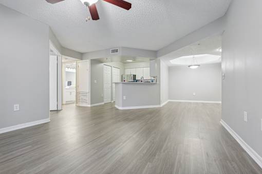 the living room and kitchen of an empty house with wood floors and a ceiling fan at Pembroke Pines Landings, Florida, 33025
