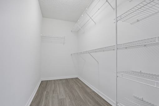 an empty room with white walls and wood flooring and a white closet with shelves at Pembroke Pines Landings, Pembroke Pines, Florida