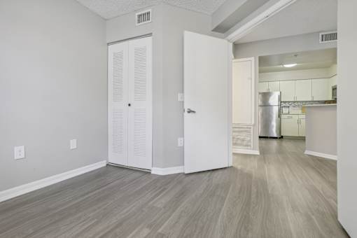 the living room and kitchen of an apartment with white walls and wood flooring at Pembroke Pines Landings, Pembroke Pines, Florida, 33025