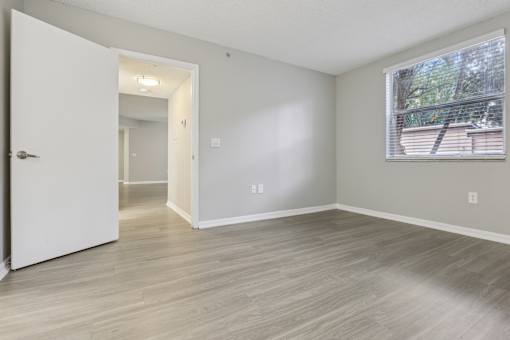 an empty living room with a large window and wood flooring at Pembroke Pines Landings, Pembroke Pines, FL 33025