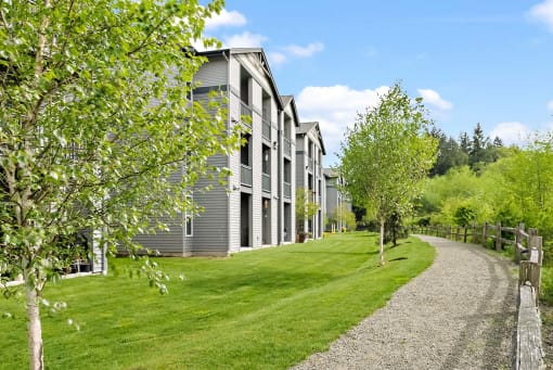 a path leading to a row of houses on a green field