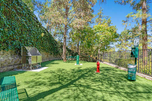 A green lawn with a red fire hydrant and a green trash can.