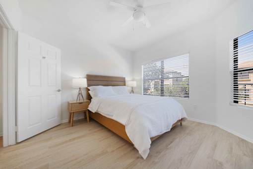 A bedroom with a bed, nightstand, and window with blinds.