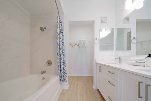 A white bathroom with a tub, sink, and mirror.