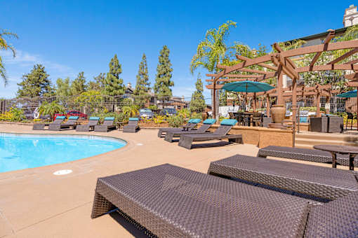 A pool area with sun loungers and a shaded seating area.