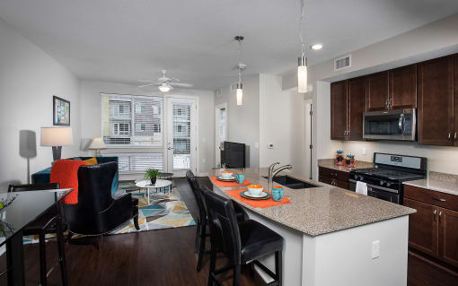 an open apartment space with large windows, an island and seating, and large windows