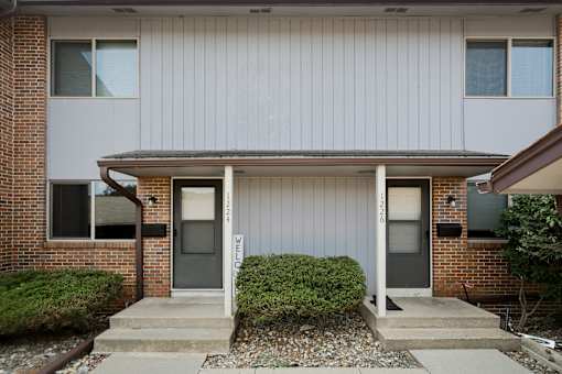 A house with a grey front and a brick wall.