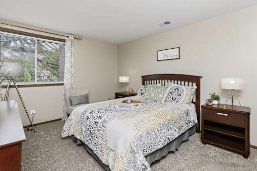 A bedroom with a bed, nightstand, and window.