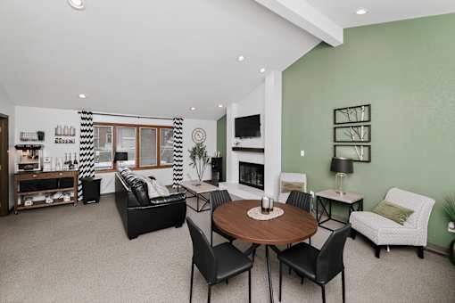 A living room with a fireplace and a dining table.